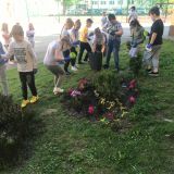 Uczniowie klasy I a sadzą kwiaty przed szkołą.