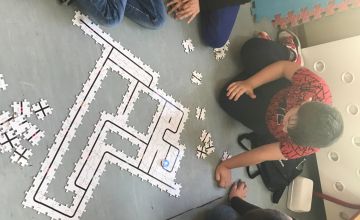 Uczniowie klasy IIA w trzech grupach układają z puzzli drogę dla robota Ozobota.