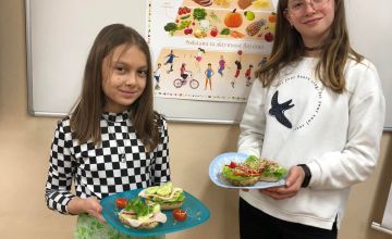 Na zdjęciach widać uczniów klasy 6a na tle plakatu Piramida zdrowia. Na talerzach dzieci mają kolorowe kanapki.